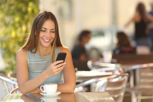 Woman sitting at table smiling at her cell phone